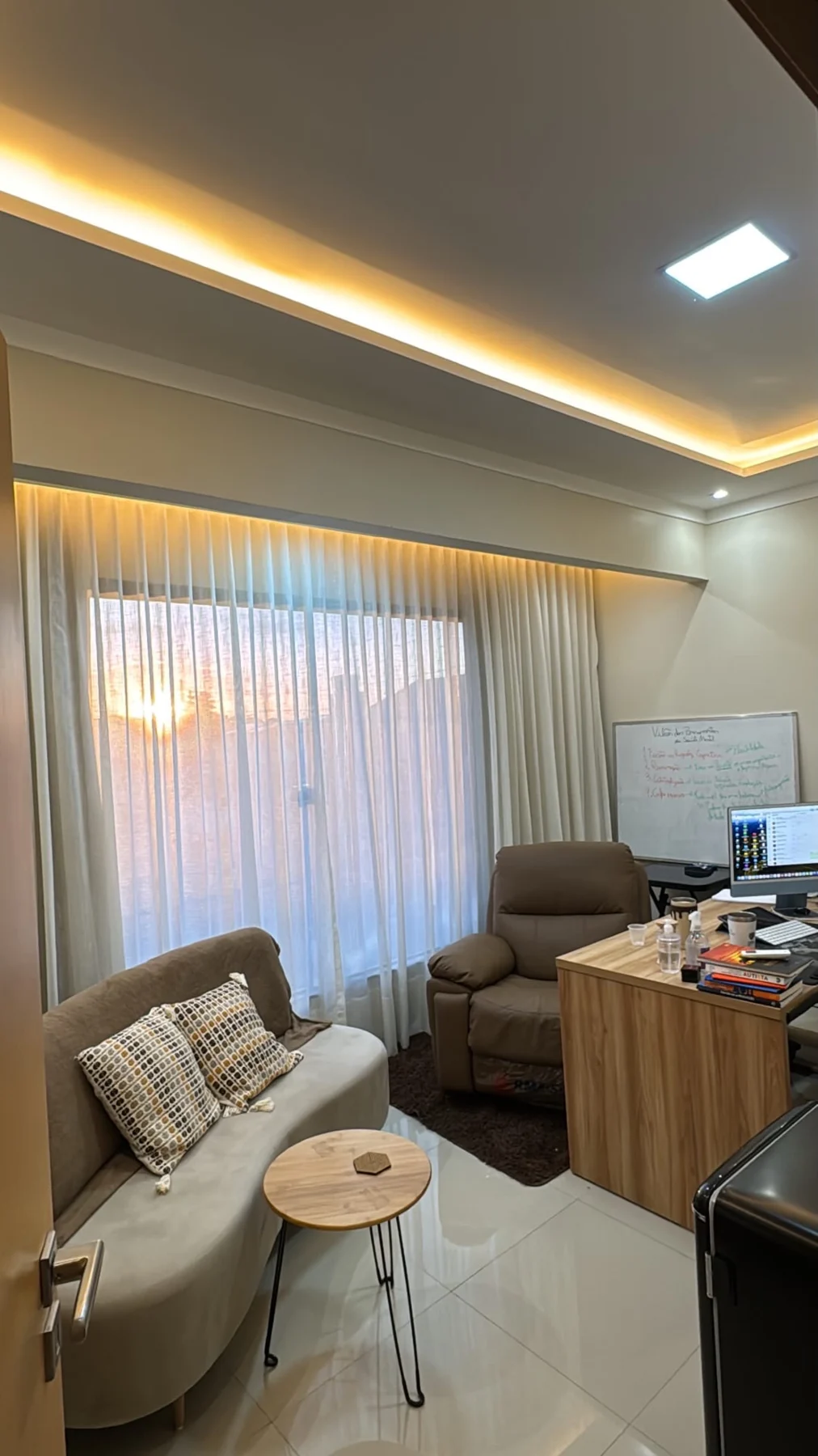 Sala real do consultório com sofá, poltrona e iluminação acolhedora